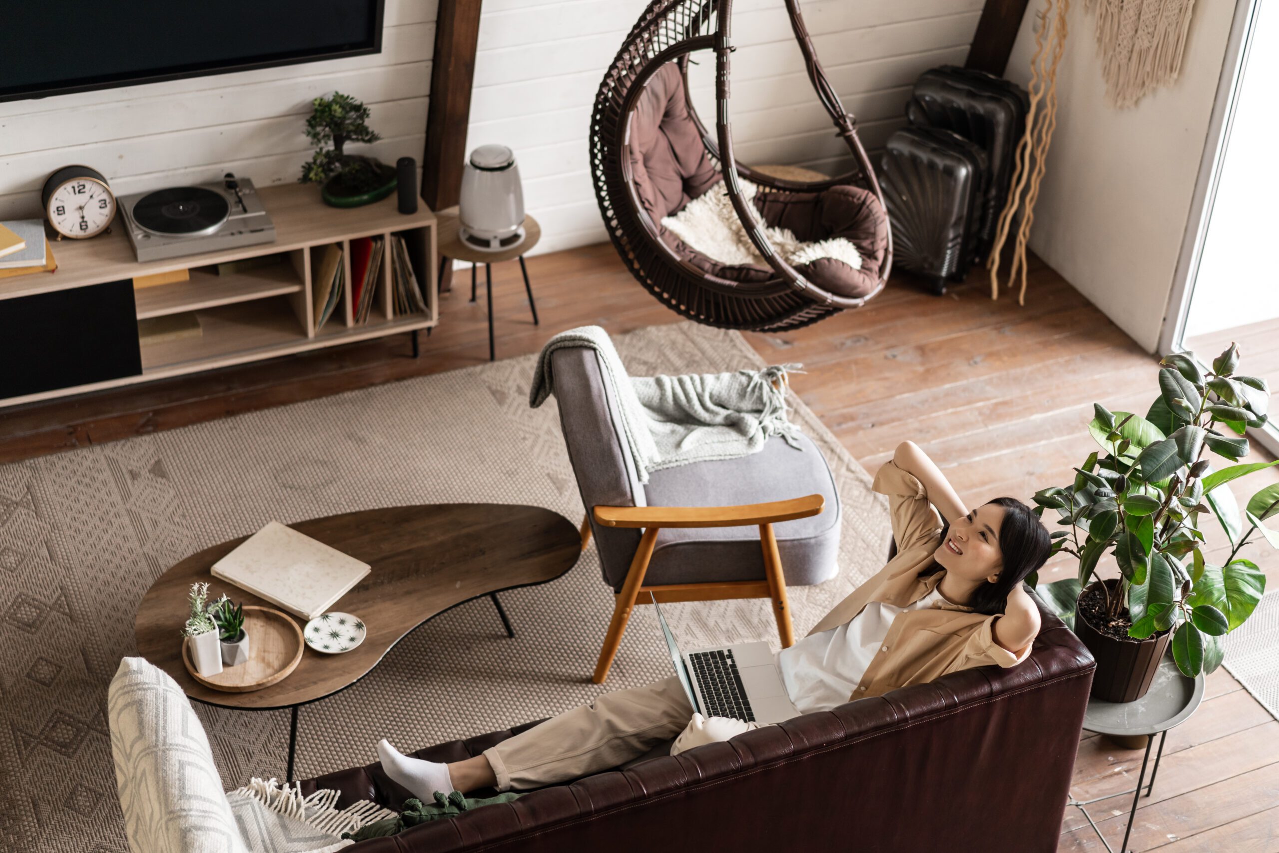 happy relaxed asian woman laying couch home with laptop listening podcast enjoying weekend scaled